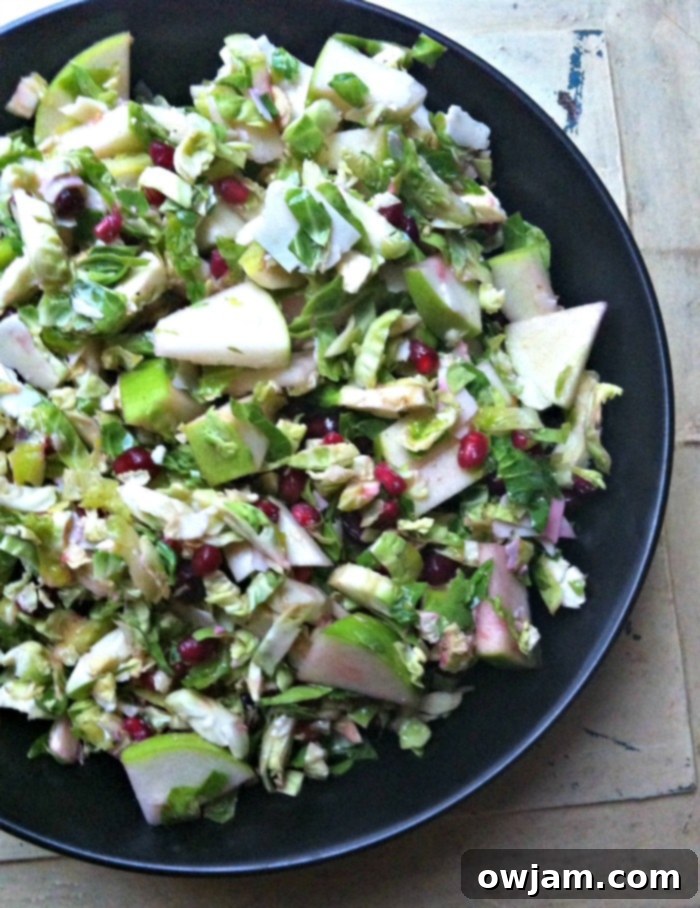 Crisp Shaved Brussels Sprout Salad with Apple and Pomegranate 4 A large bowl of the healthy Shaved Brussels Sprout Salad, highlighting the colorful ingredients.