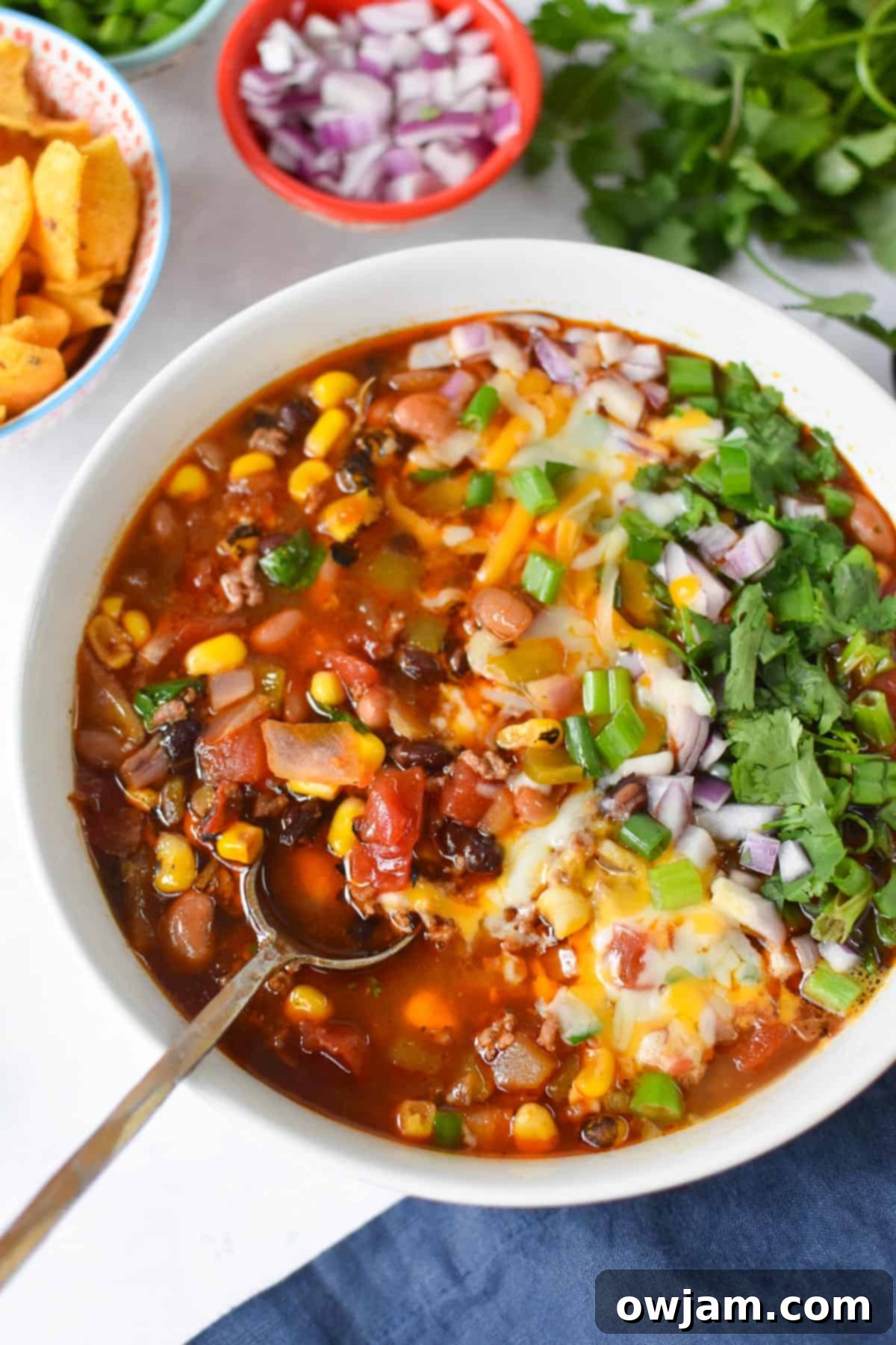 Slow Cooker Taco Soup Recipe with spoon in a white bowl, garnished with cilantro and sour cream
