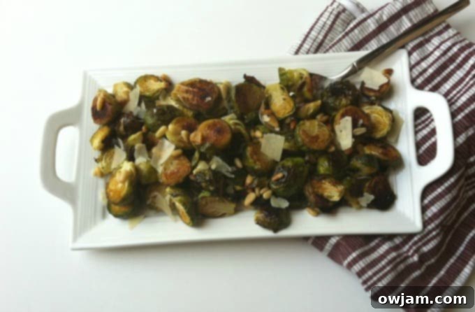 A serving bowl of roasted Brussels sprouts, garnished with fresh lemon and herbs