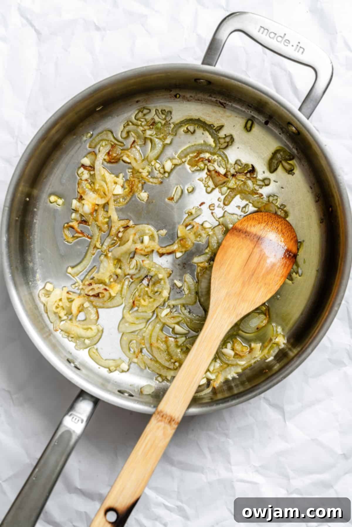 Lebanese Green Bean Stew 5 Sliced onions and minced garlic sizzling in golden olive oil in a large pan, forming the aromatic base for Lebanese Green Beans.