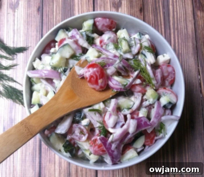 Vibrant Cucumber Tomato Salad with Zesty Dill Yogurt 12 A vibrant Cucumber Tomato Salad with Dill Yogurt Dressing in a white serving bowl, garnished.