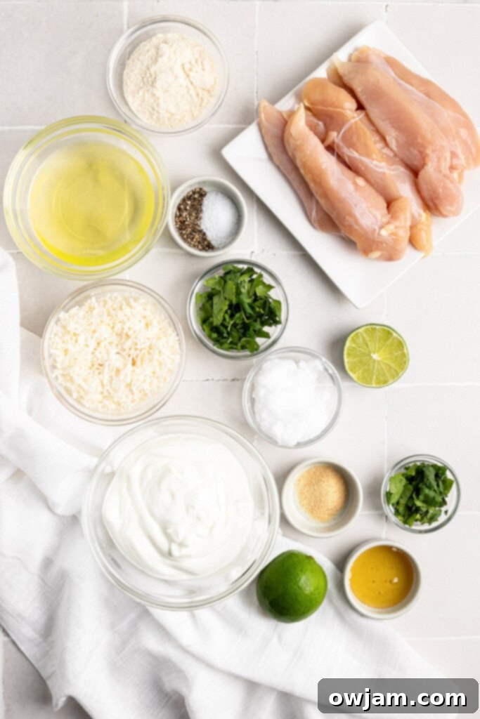Ingredients for Coconut Chicken Tenders laid out on a wooden cutting board, including chicken, coconut flakes, flour, eggs, and lime.