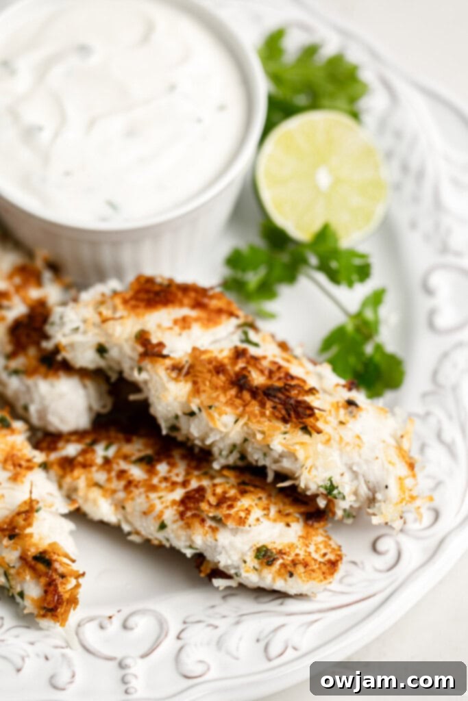 A close-up of crispy Coconut Chicken Tenders arranged neatly on a white plate, ready to be served.