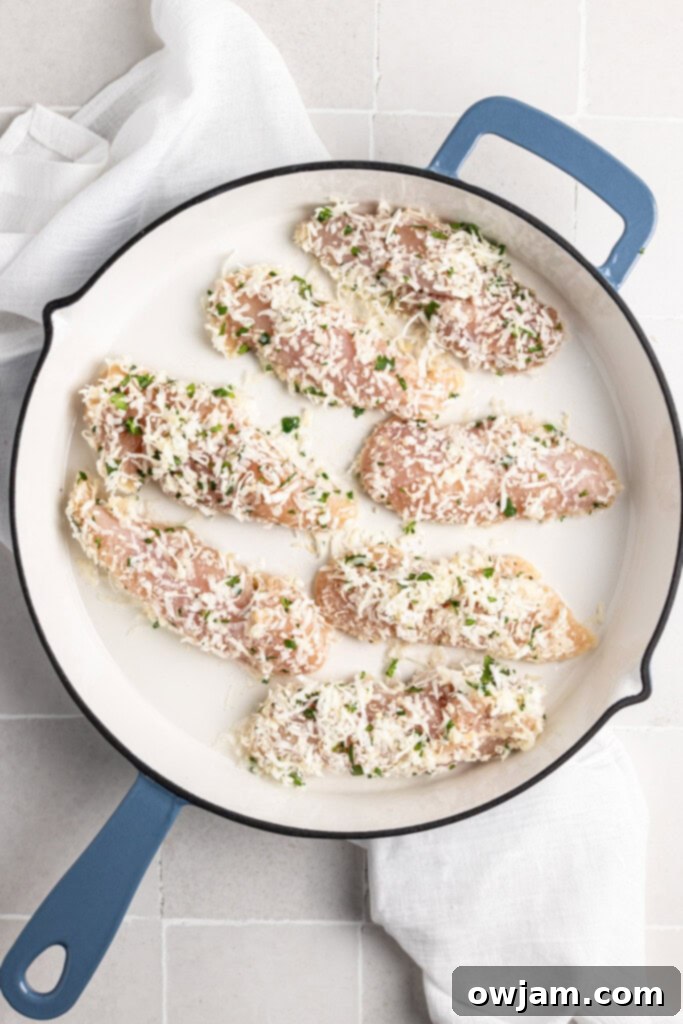 Coconut Chicken Tenders cooking in a large skillet, sizzling to a golden brown.