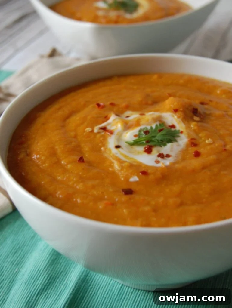 A top-down view of the Moroccan Carrot Red Lentil Soup, garnished generously with fresh cilantro, inviting you to take a spoonful.
