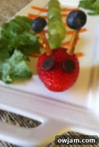 A finished fruit caterpillar snack on a plate, ready to be eaten by a happy child.