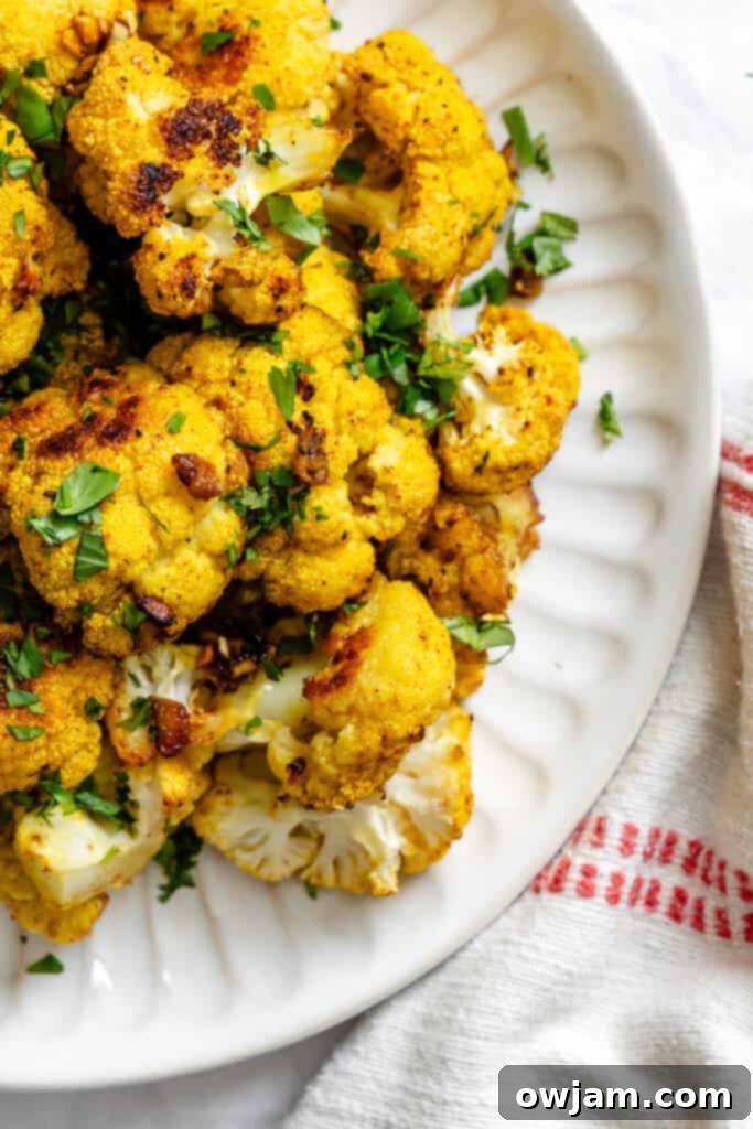 Golden Curry Roasted Cauliflower 2 Curry Roasted Cauliflower on white plate, garnished with fresh cilantro, ready to be served