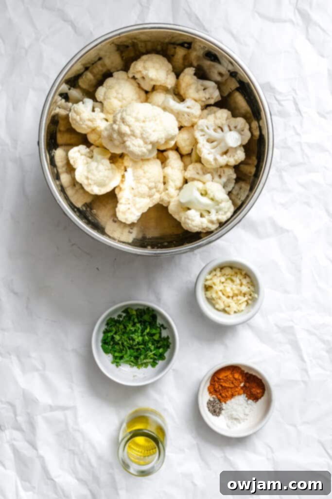Golden Curry Roasted Cauliflower 4 Ingredients for Curry Roasted Cauliflower laid out, including a head of cauliflower, olive oil, and spices