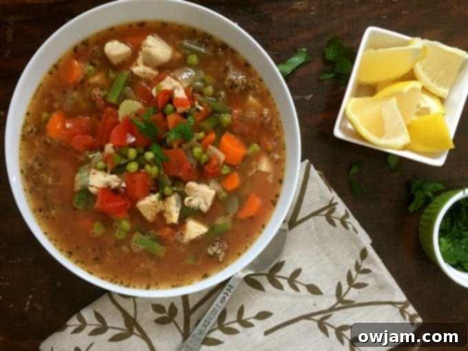 A close-up of a spoon scooping a rich and flavorful Chicken Quinoa Soup, showing the texture of quinoa, chicken, and vegetables.