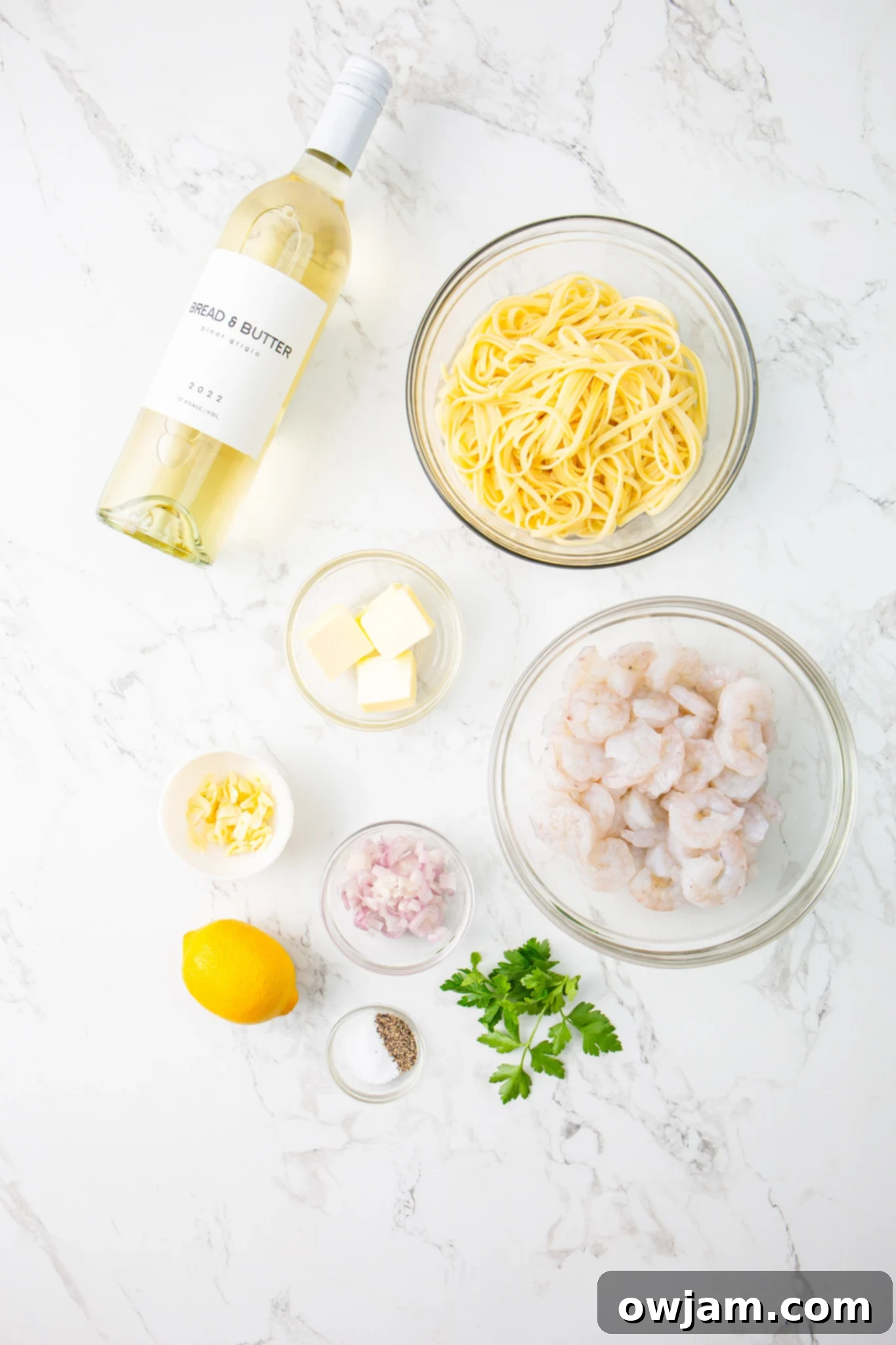 Zesty Lemon Garlic Shrimp Pasta 4 Ingredients for Lemon Garlic Shrimp Pasta laid out on a wooden board: linguine, butter, garlic, onion, shrimp, lemon, white wine, and parsley.