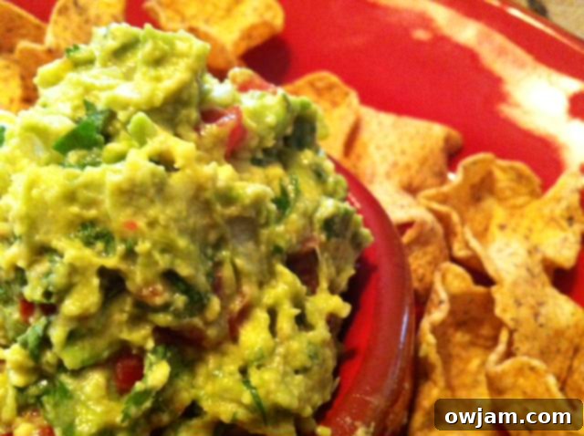 Close-up detailed view of textured guacamole, highlighting fresh ingredients.