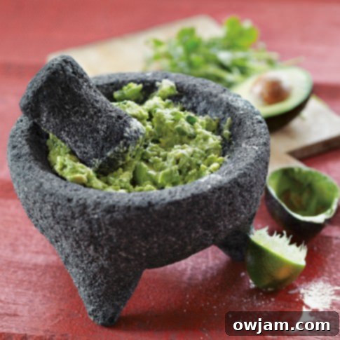 A beautiful lava stone molcajete (mortar and pestle) filled with freshly made guacamole, serving as both a tool and a dish.