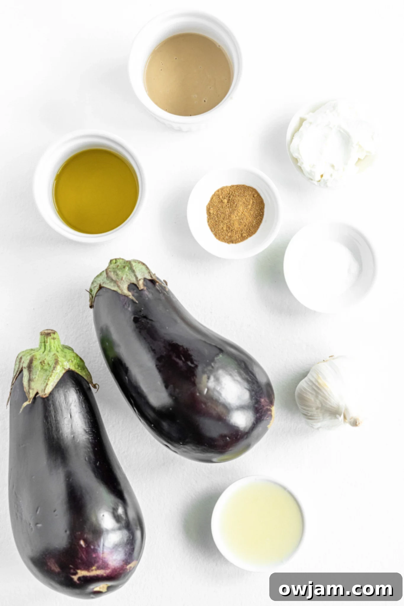 Fresh ingredients for Baba Ghanoush: whole eggplants, lemon, garlic, olive oil, and tahini.