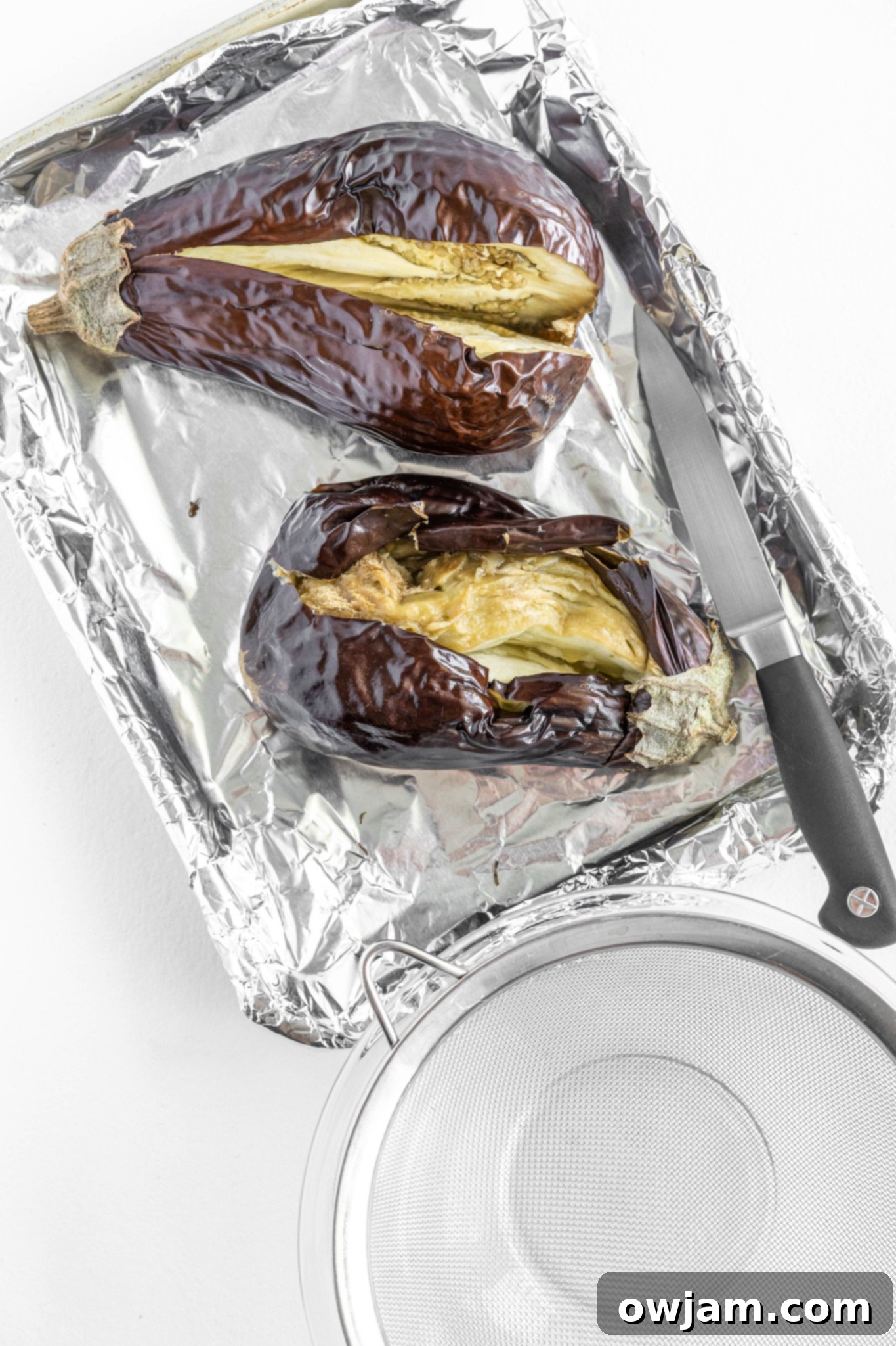 Scooping out the soft, cooked flesh from a roasted eggplant for Baba Ghanoush.