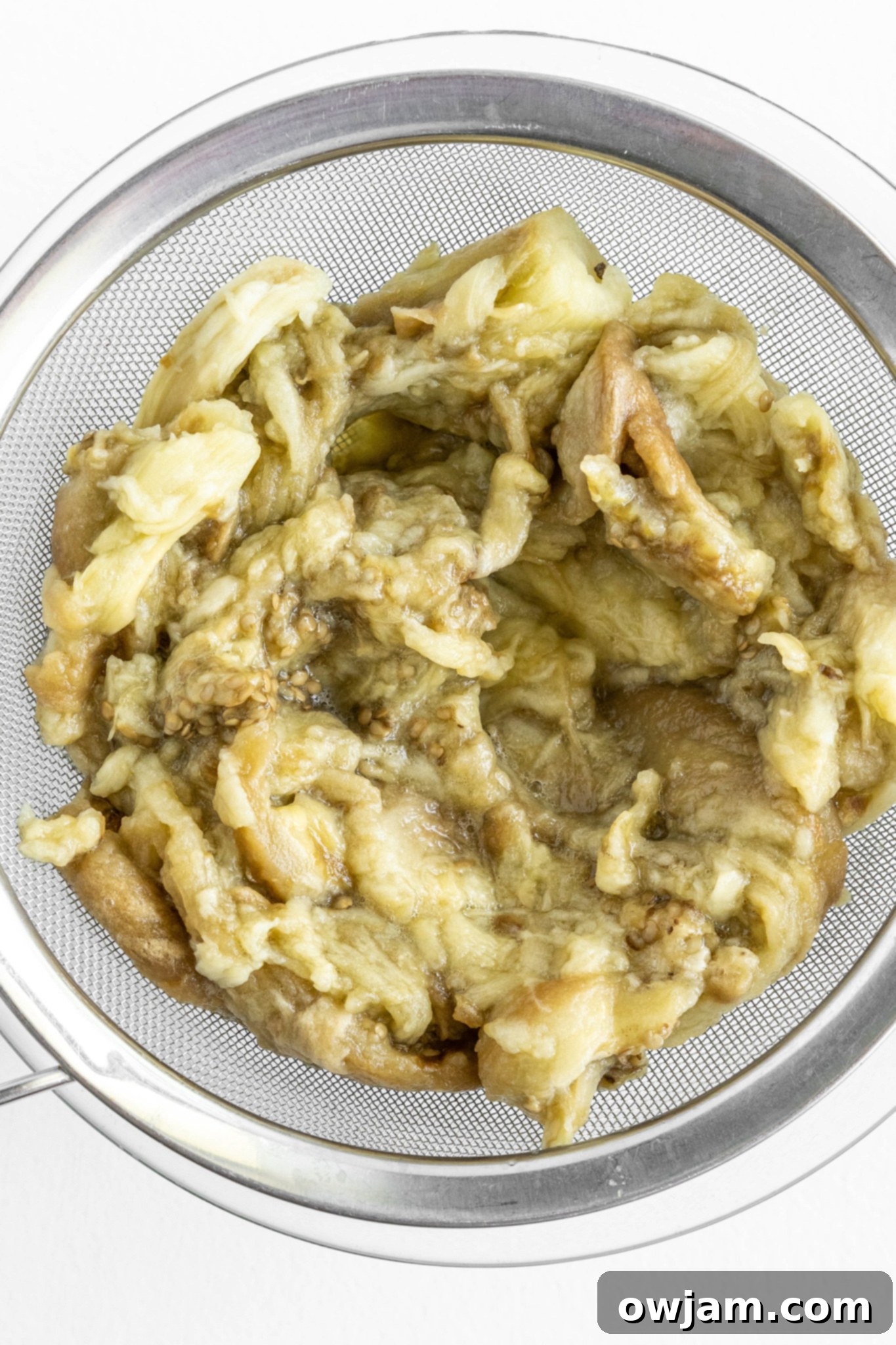 Strained eggplant flesh in a fine mesh sieve, draining excess liquid.