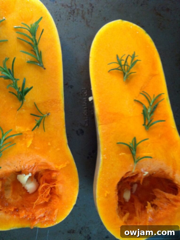 Butternut squash halves with butter and fresh rosemary sprigs, ready for roasting for the soup