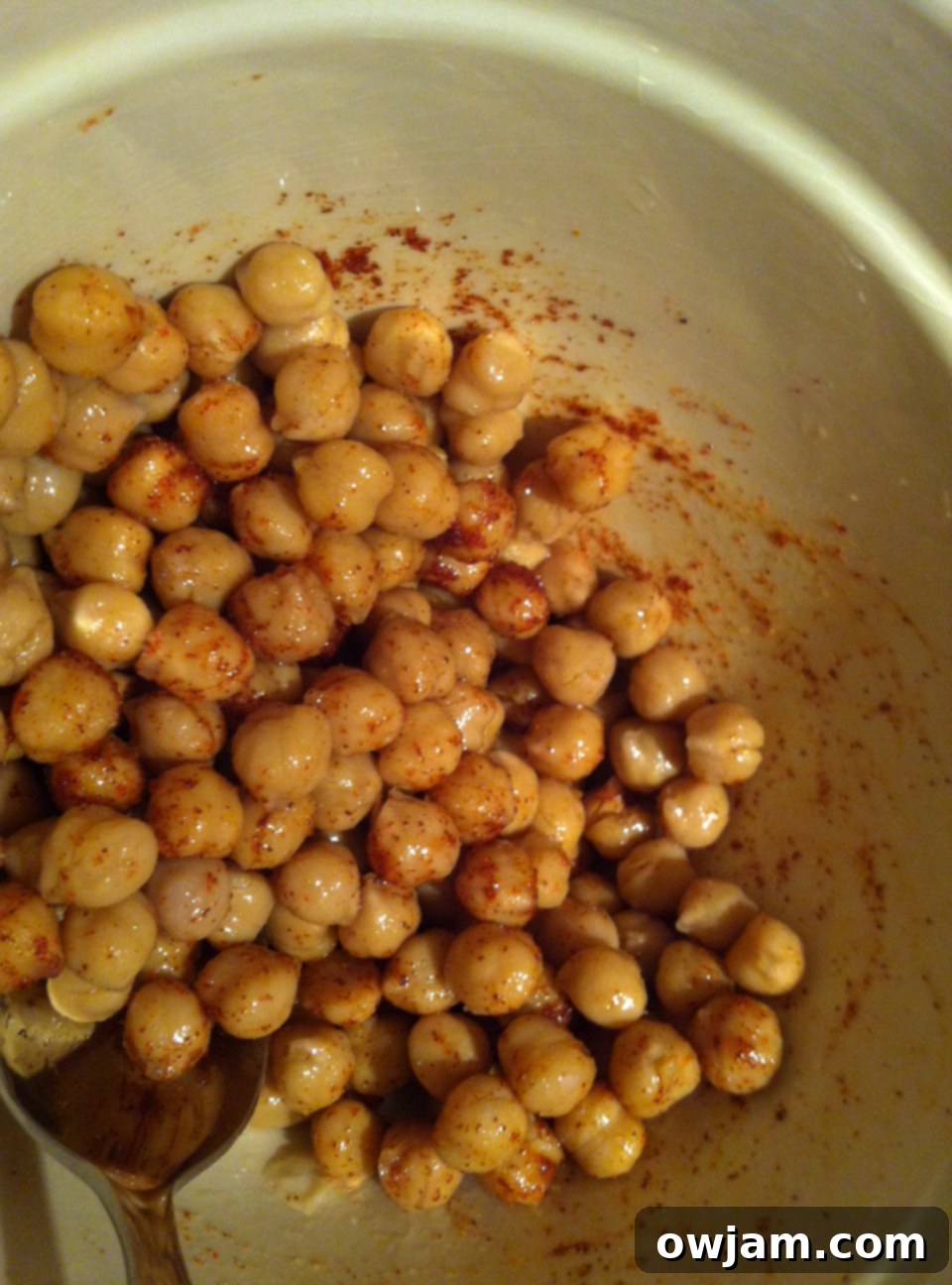 Chickpeas in a bowl tossed with olive oil, salt, and cayenne pepper.