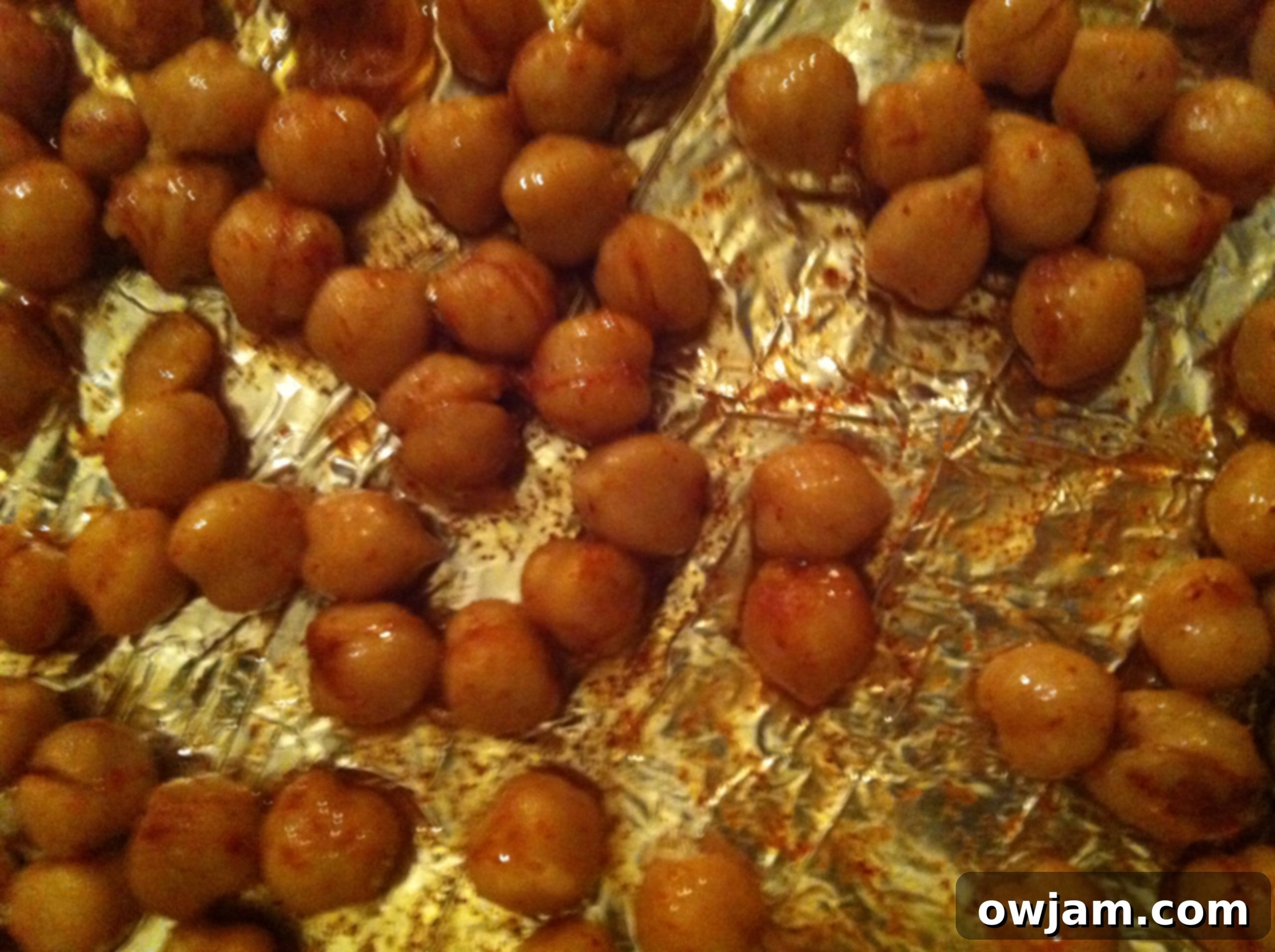 Chickpeas spread in a single layer on a baking sheet, ready for the oven.