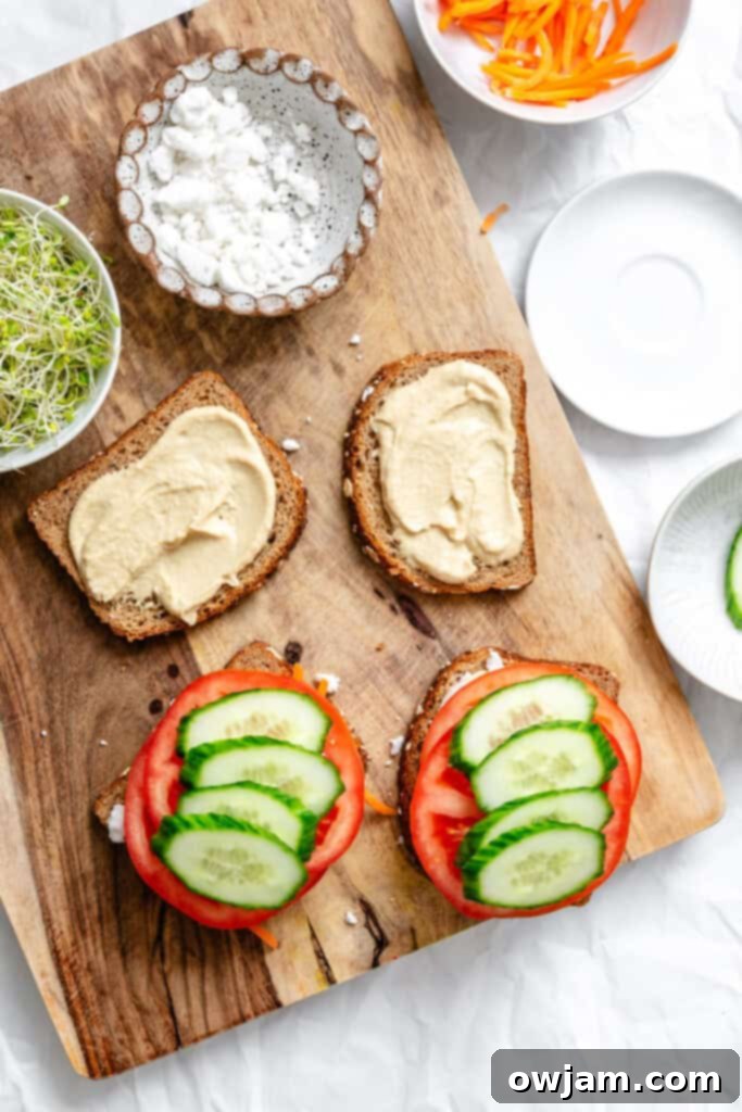 Mediterranean Garden Sandwich 8 Tomatoes and cucumbers being layered on bread with hummus and feta