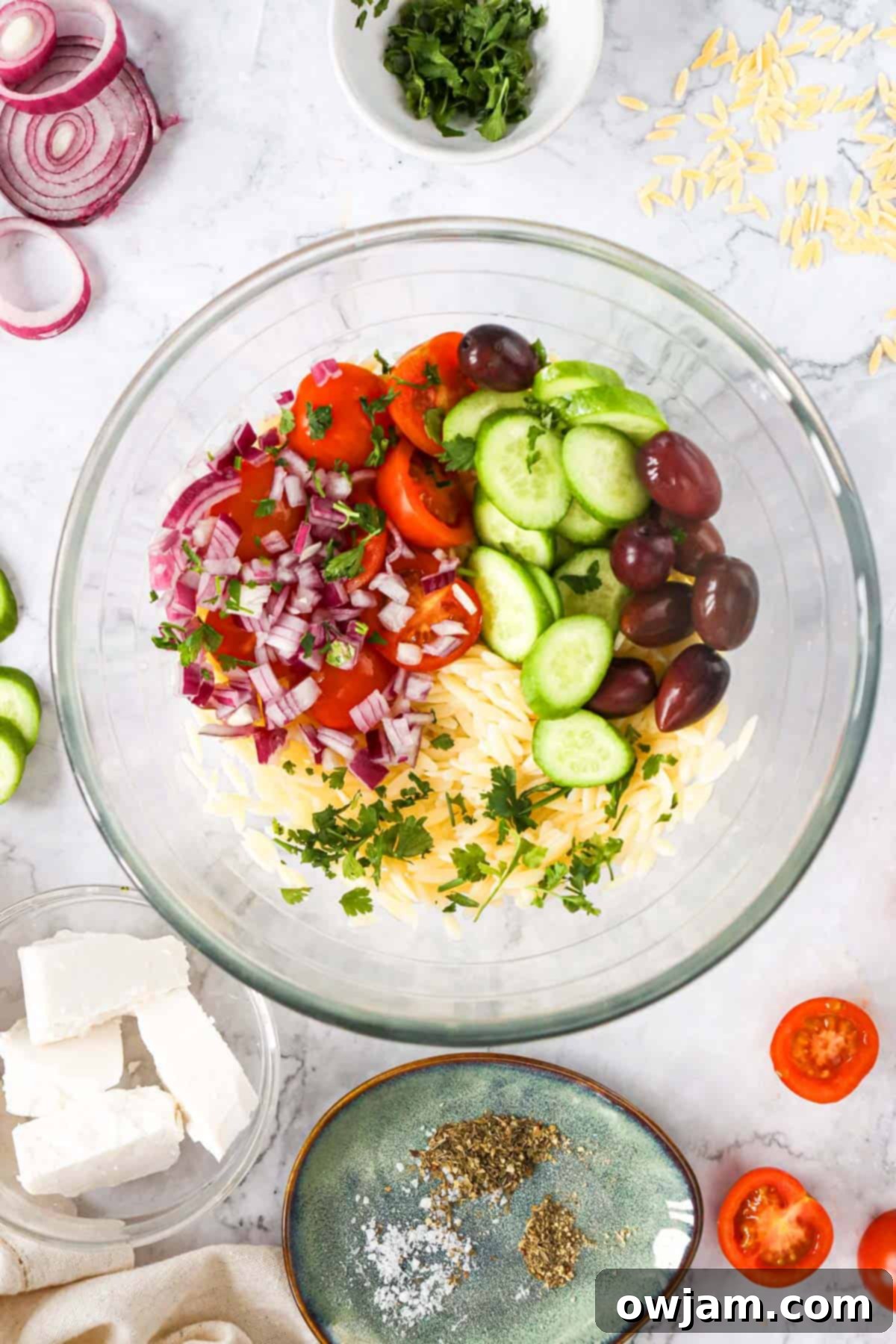 Zesty Mediterranean Orzo Salad 5 Greek Orzo Pasta Salad ingredients being mixed in a large bowl.
