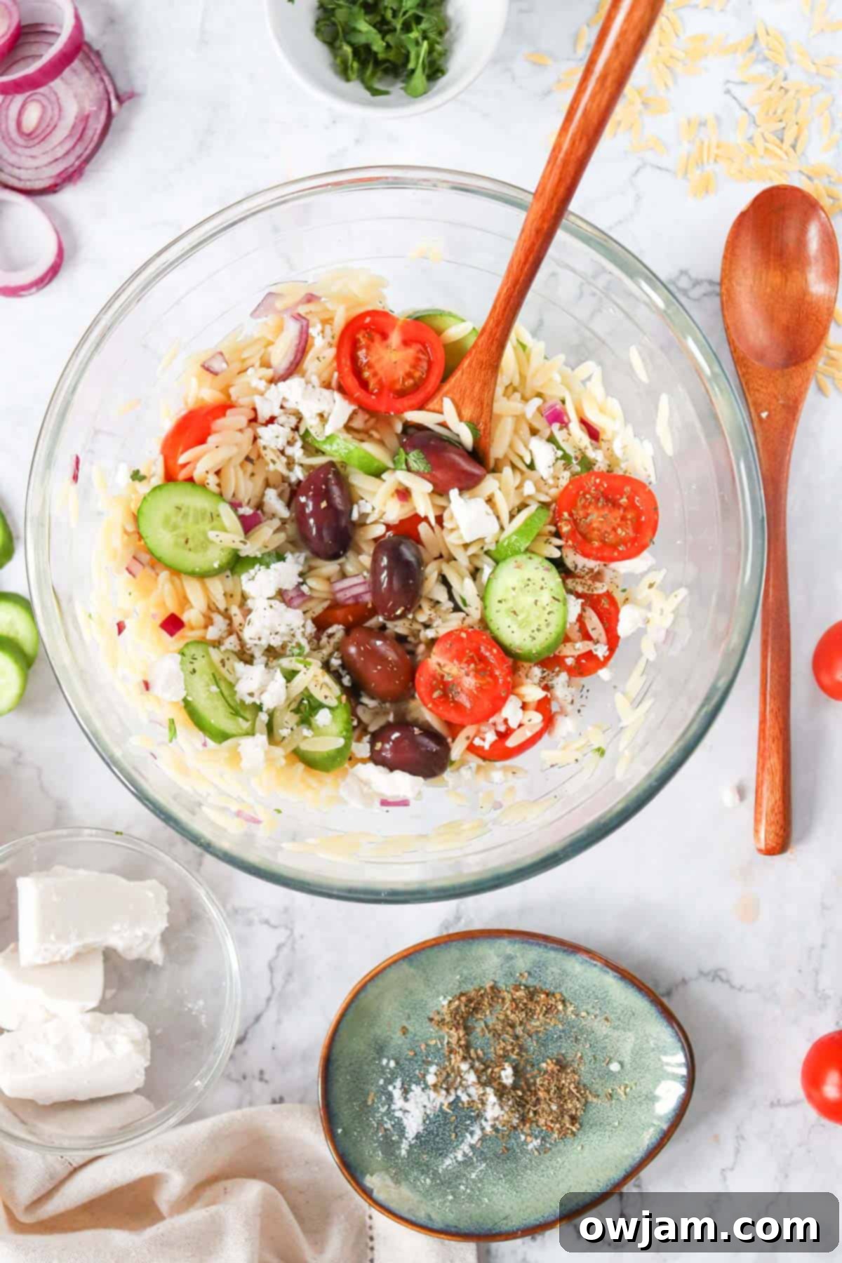 Zesty Mediterranean Orzo Salad 6 Close-up of Greek Orzo Pasta Salad with a wooden spoon in a bowl.