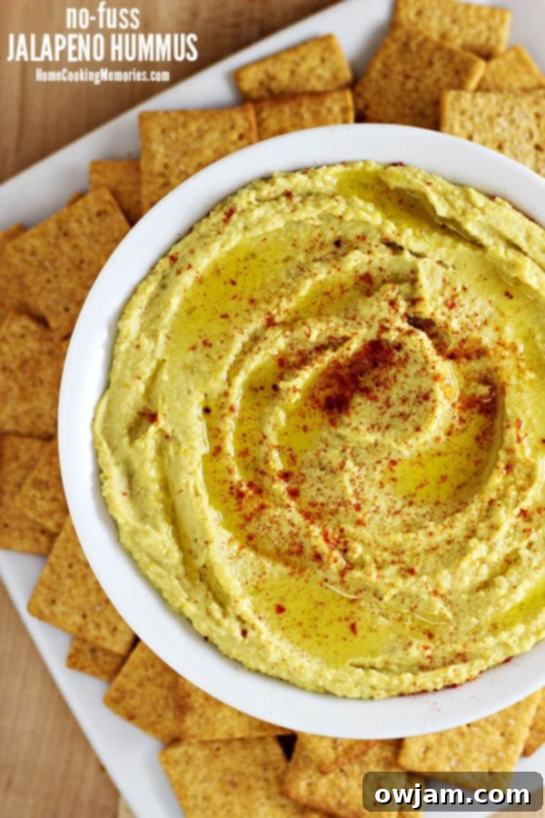 Spicy Jalapeño Hummus in a white bowl, garnished with sliced jalapeños
