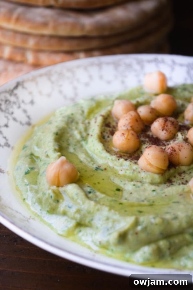 Vibrant green cilantro hummus in a bowl, garnished with fresh cilantro leaves