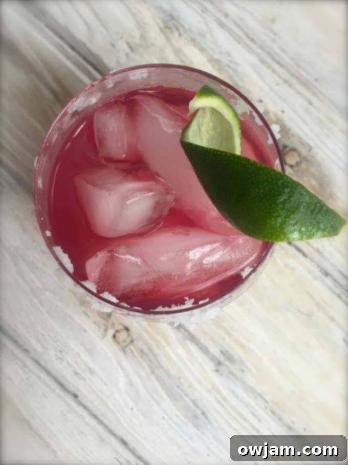 Pomegranate Margarita in a salt-rimmed glass, garnished with lime.