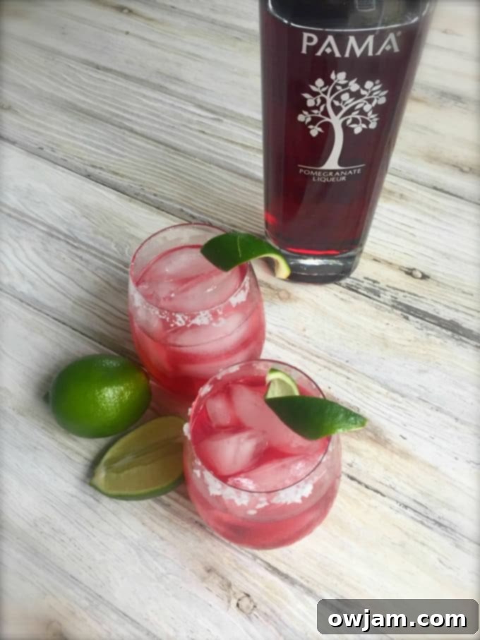 Two Pomegranate Margaritas with fresh lime and pomegranate seeds.