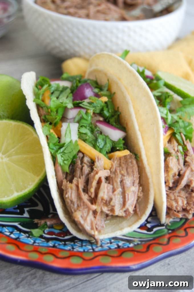 Flavorful Slow Cooker Shredded Beef Tacos 3 Close-up of Slow Cooker Shredded Beef Tacos with fresh garnishes like cilantro and lime wedges.