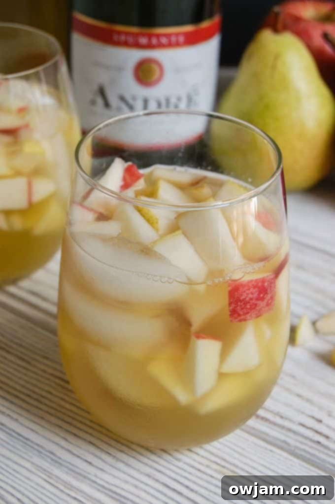Orchard Sparkle Sangria 6 Close-up view of a pitcher of sparkling apple pear sangria, showing the fruit