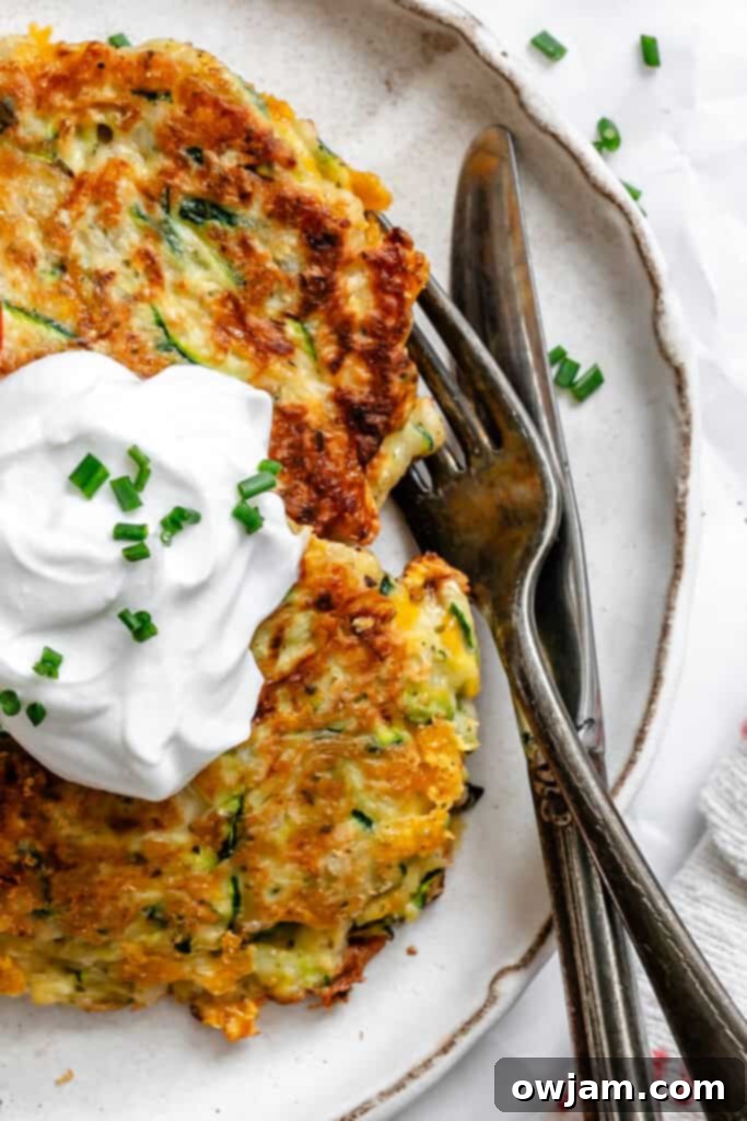Effortless Zucchini Fritters 5 Platter of freshly cooked Easy Zucchini Fritters, golden brown and garnished, ready to be served.