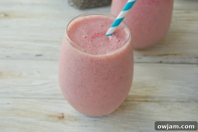 Strawberry Banana Chia Delight 3 Close-up of a Strawberry Banana Chia Smoothie with a straw, showcasing its creamy texture and small chia seeds.