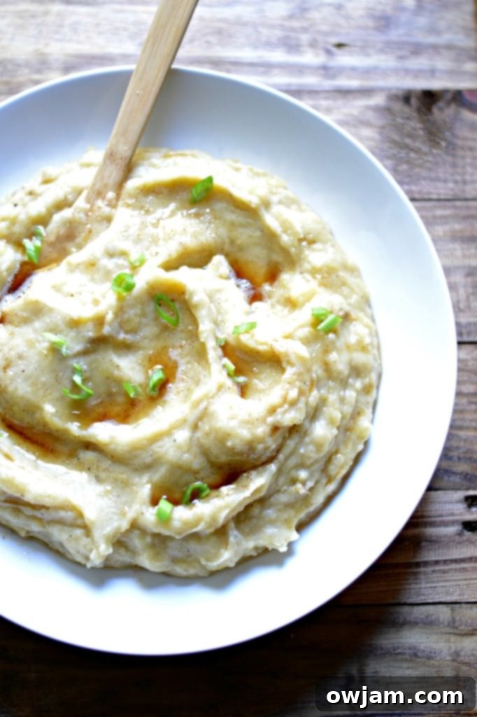 Close-up of creamy slow cooker garlic and brown butter mashed potatoes, garnished with fresh herbs.