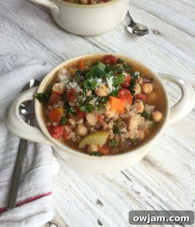 A steaming bowl of Smoky Kale Chickpea Farro Soup, garnished with fresh herbs, ready for a cozy fall dinner.