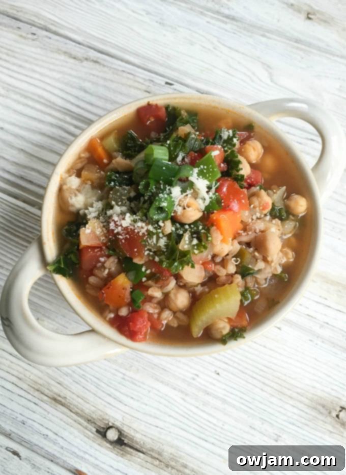 Close-up shot of the rich, colorful broth and ingredients in Smoky Kale Chickpea Farro Soup.