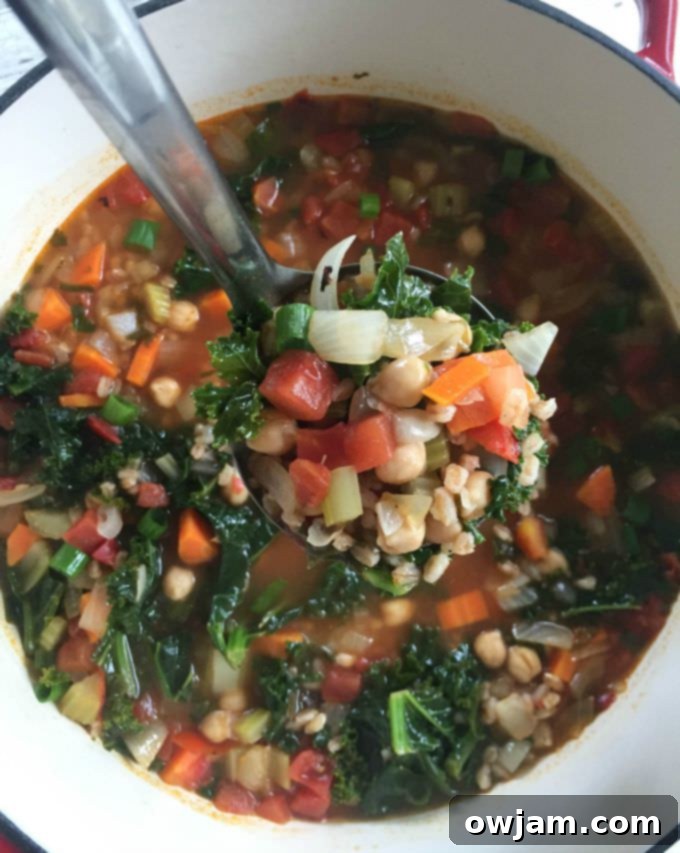 A close-up of a rustic bowl of Smoky Kale Chickpea Farro Soup, highlighting its wholesome ingredients and inviting texture.