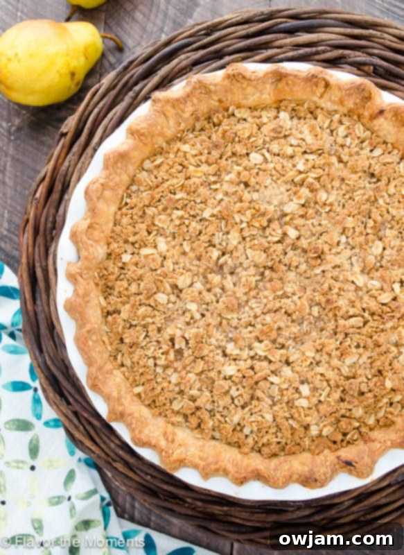 A rustic Pear Ginger Crumble Pie, showing a golden crumb topping and juicy pear filling.