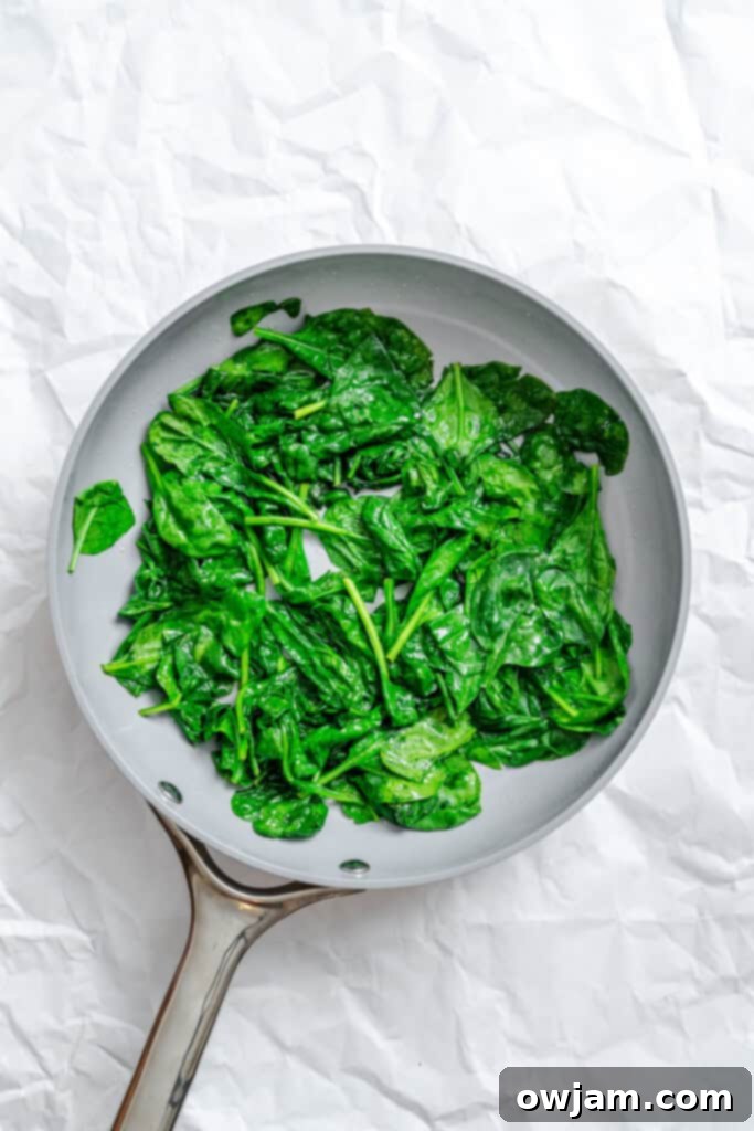 Cheesy Black Bean Egg Bake spinach wilting in a skillet
