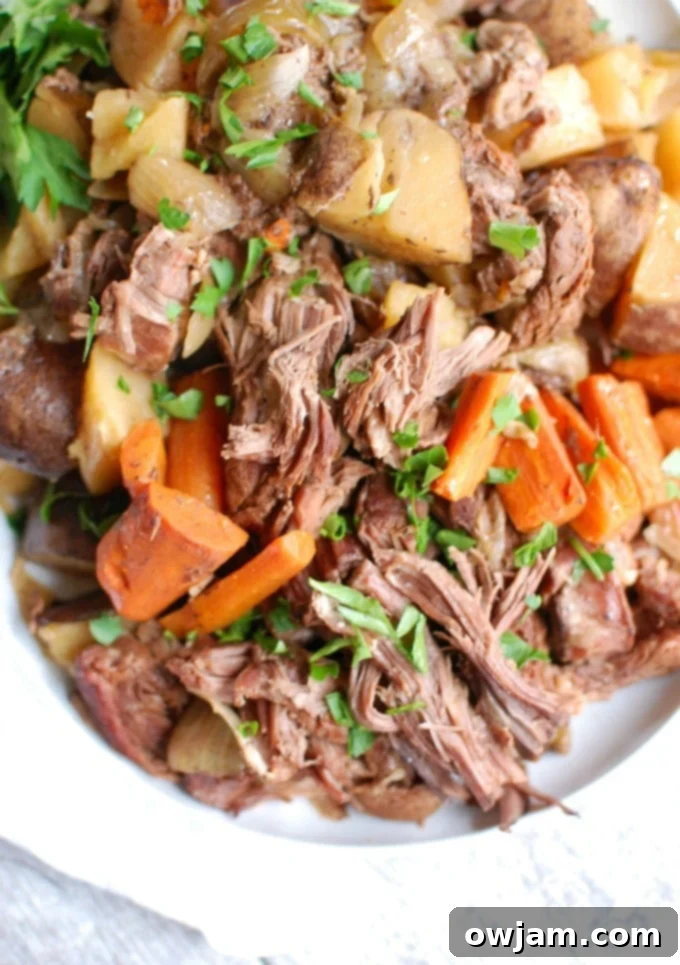 Tender Slow Cooker Chuck Roast 3 Crockpot Chuck Roast Recipe on white plate garnished with fresh parsley