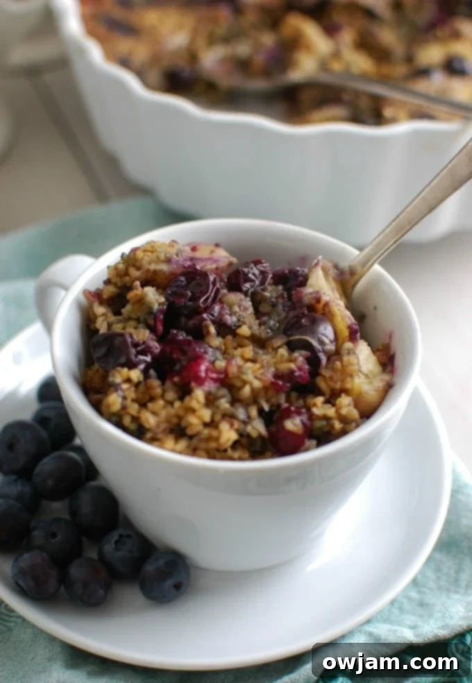 A warm bowl of Baked Blueberry Banana Steel Cut Oatmeal with fresh blueberries and banana slices, ready for breakfast