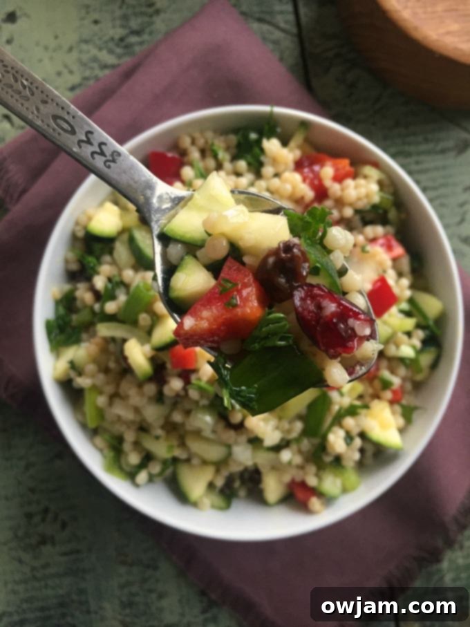 A vibrant Israeli Couscous Salad with fresh vegetables and a bright lemon dressing, served in a bowl.