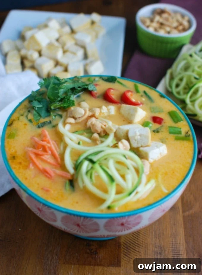 Creamy Coconut Zoodle Soup 5 Close-up of a spoon lifting zucchini noodles from Thai Coconut Zoodle Soup