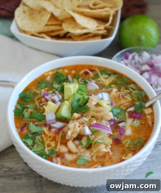 Slow Cooker White Chicken Chili in a white bowl, garnished with fresh cilantro and a dollop of sour cream. 