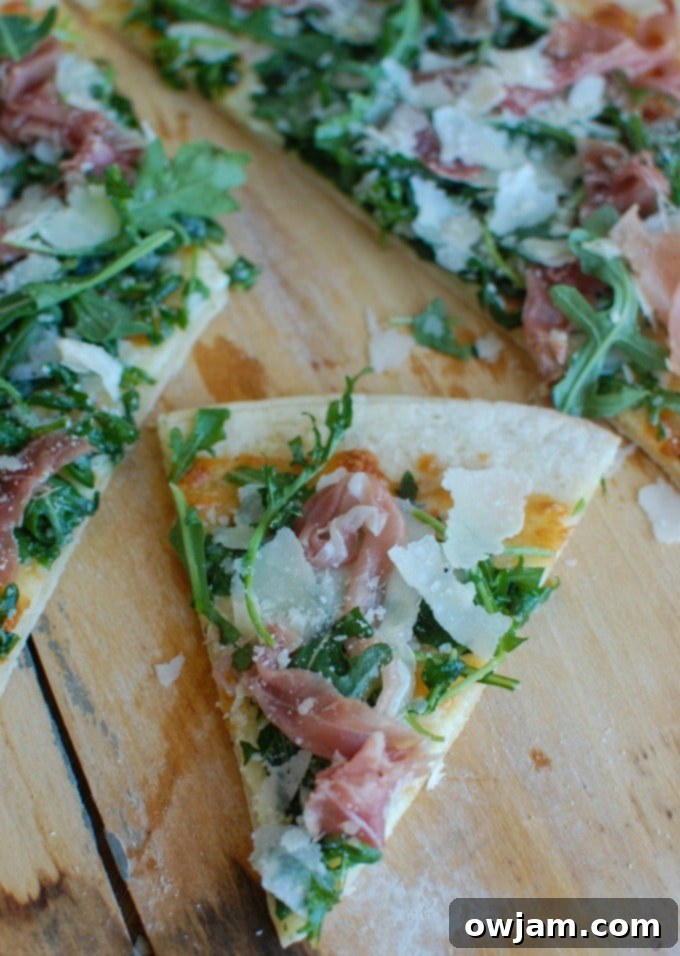Peppery Arugula Prosciutto Pie 4 A close-up shot of a single slice of Prosciutto Arugula Pizza, highlighting the delicate layers of ingredients.