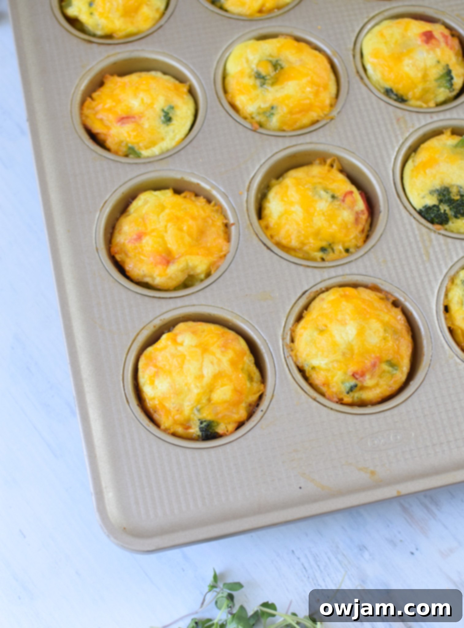 Baked Broccoli Cheddar Cups cooling in a muffin tin after being removed from the oven.