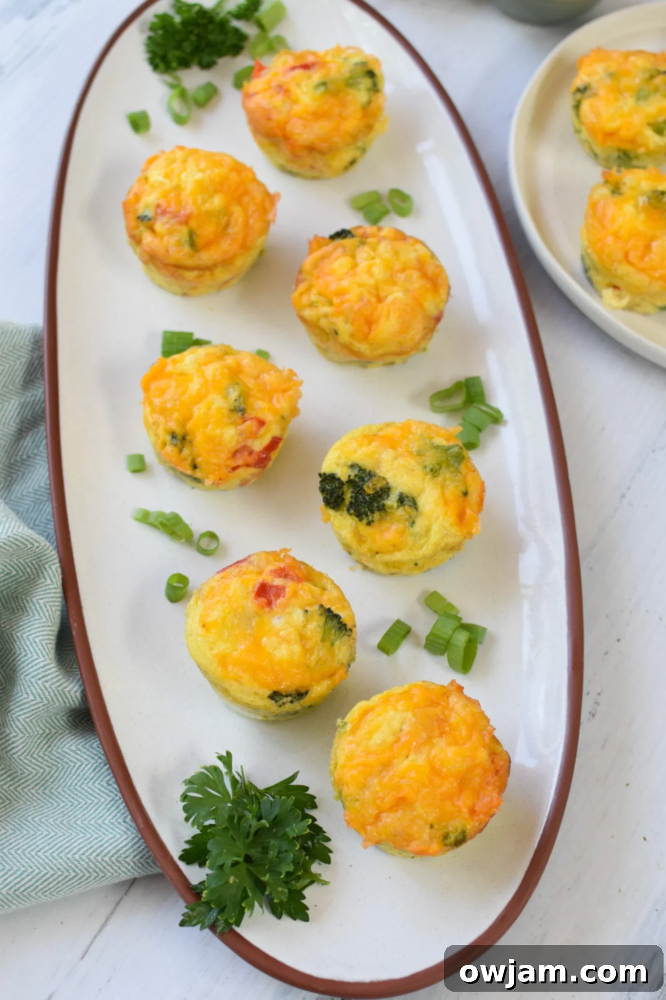 Broccoli Cheddar Cups neatly arranged on a white platter, showcasing their golden-brown edges.