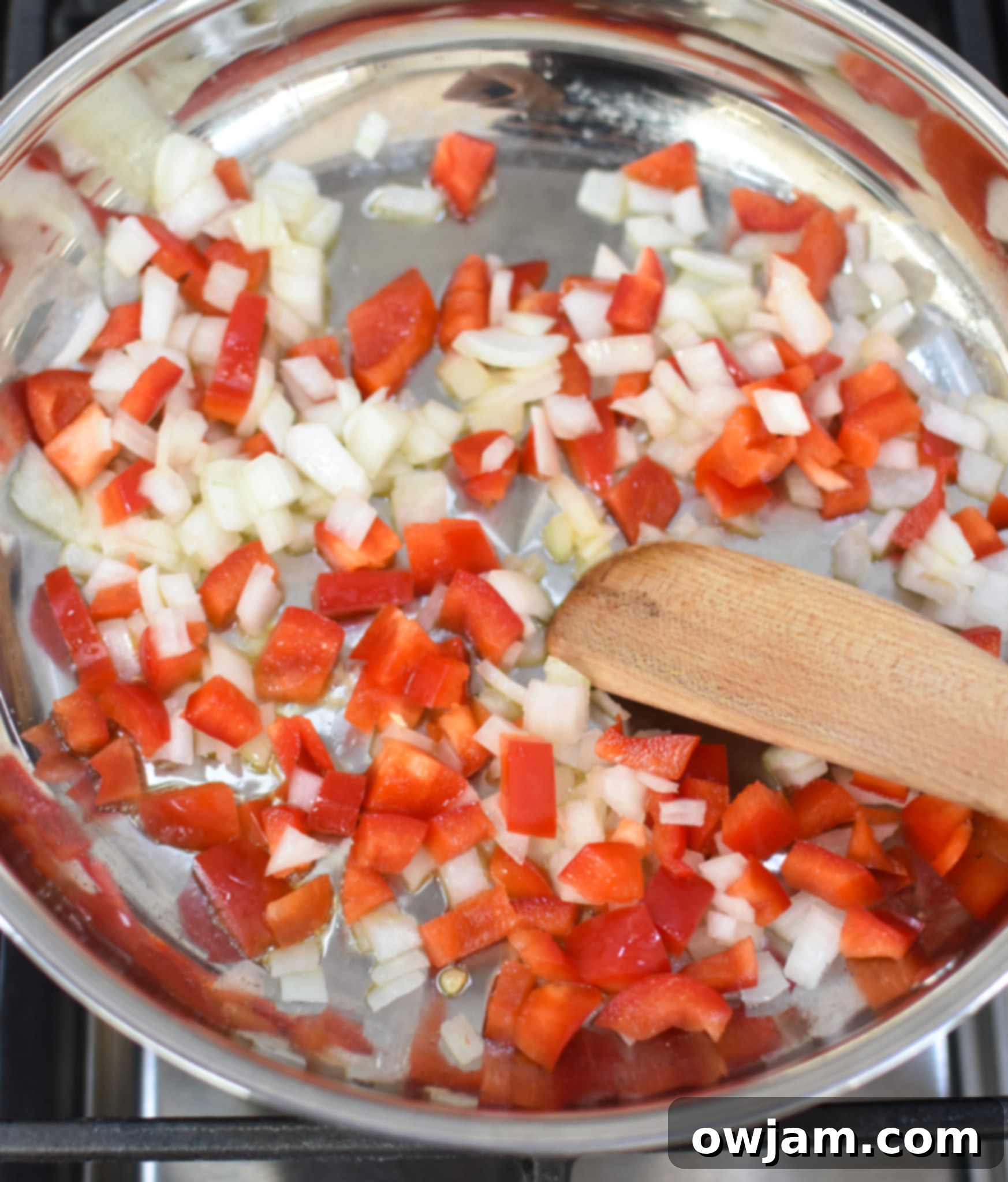 Sautéed bell peppers and onions in a skillet, ready to be added to the egg mixture.