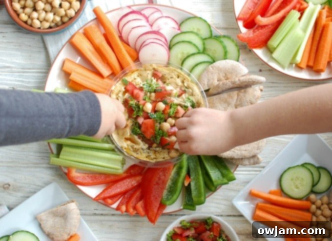 Healthy Lebanese Style Hummus with fresh toppings served with colorful vegetables and pita bread.