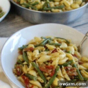 Pesto Pasta with Green Beans Sun-dried Tomatoes and Toasted Pine Nuts with spoon.